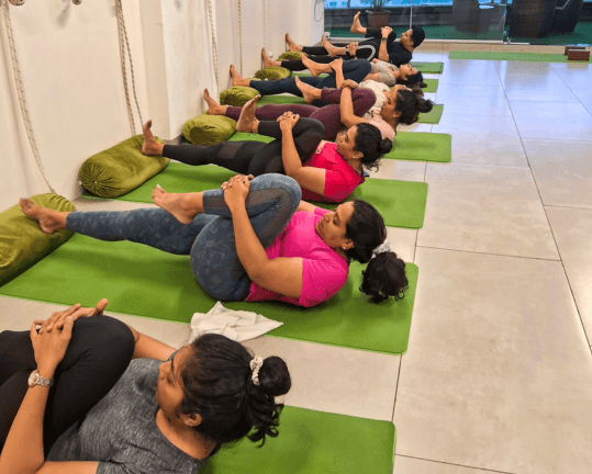 Class hugging knees to chest at the close of a session