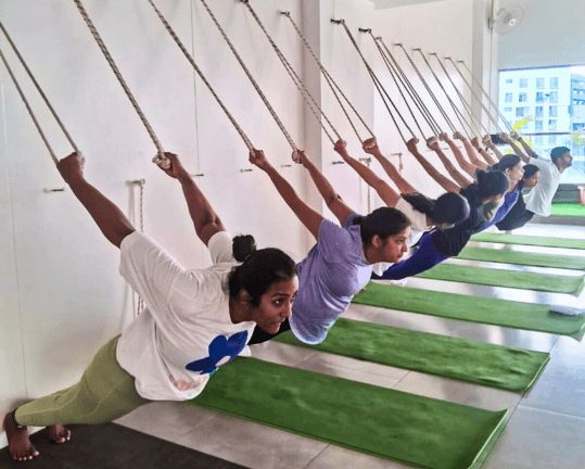 A row of students stretching forward on the rope wall